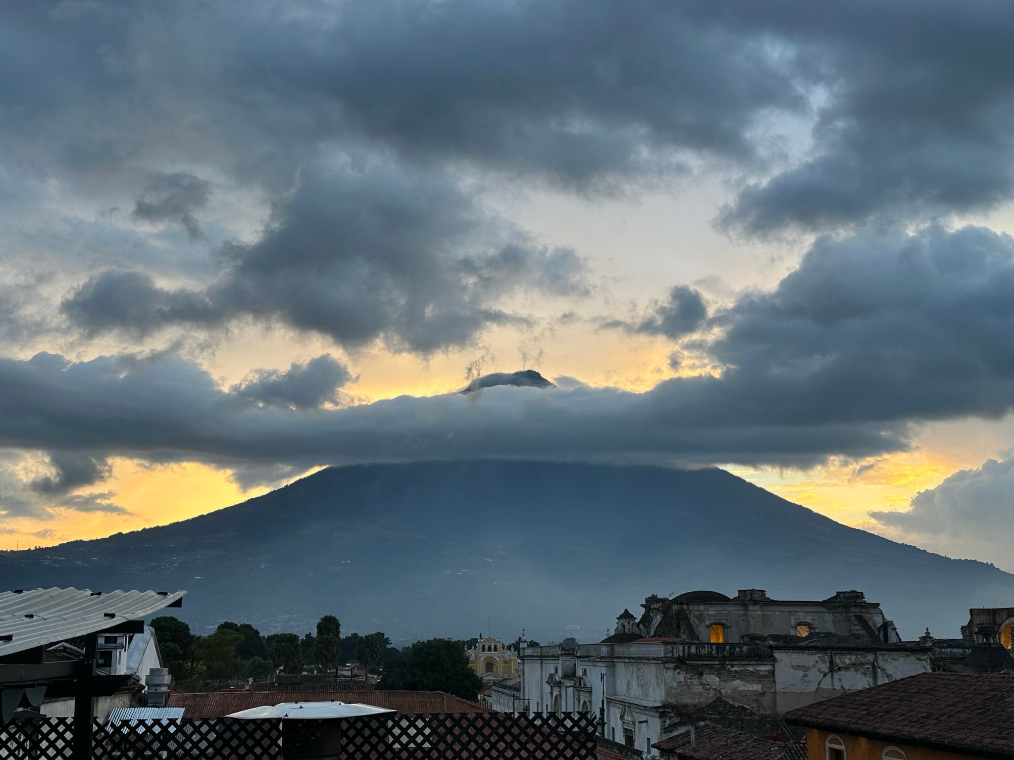 A volcano silhouetted against dusk clouds